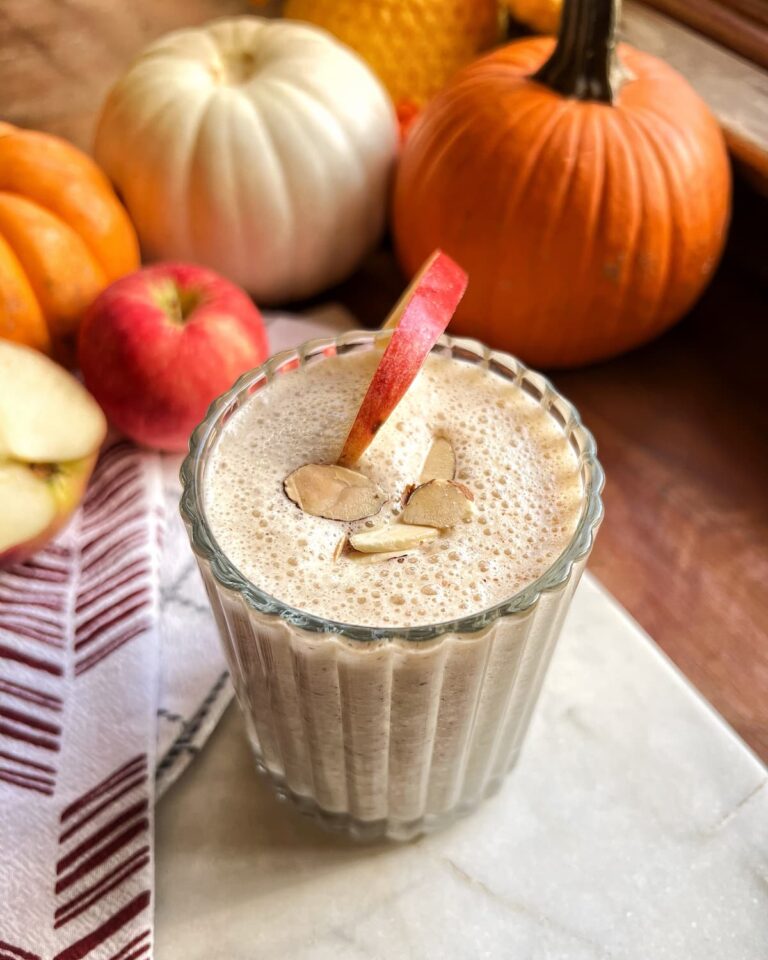 caramel apple protein smoothie in a glass with an apple slice