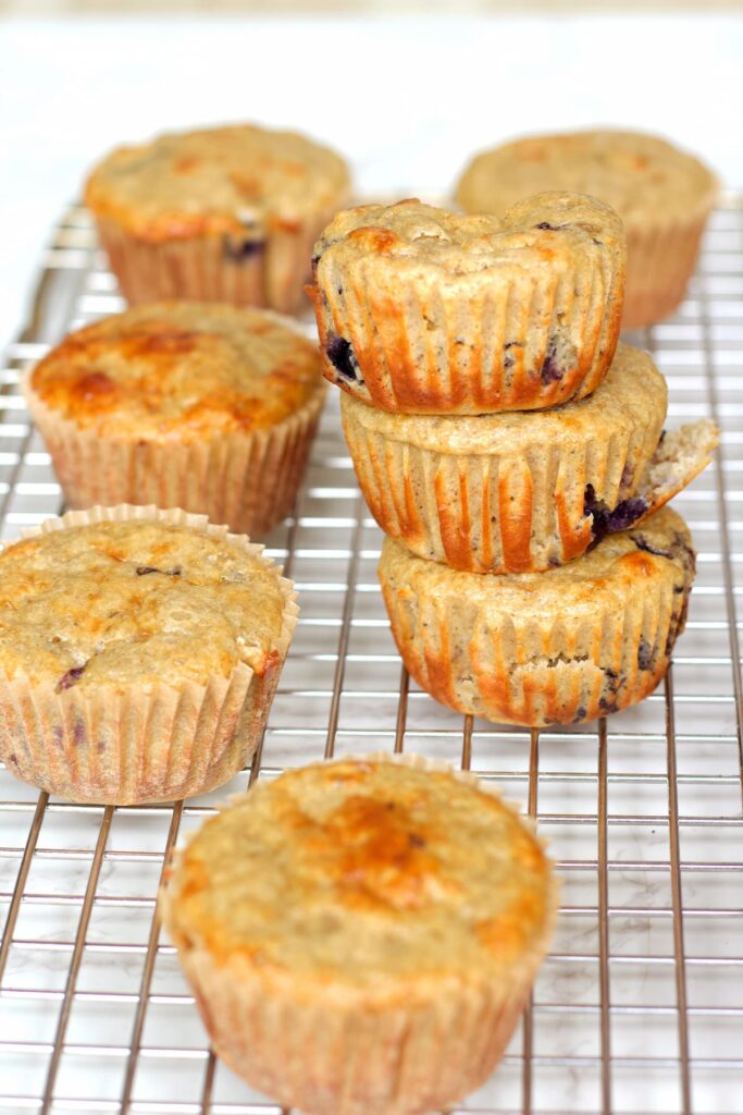 blueberry cottage cheese muffins stacked on a wire rack
