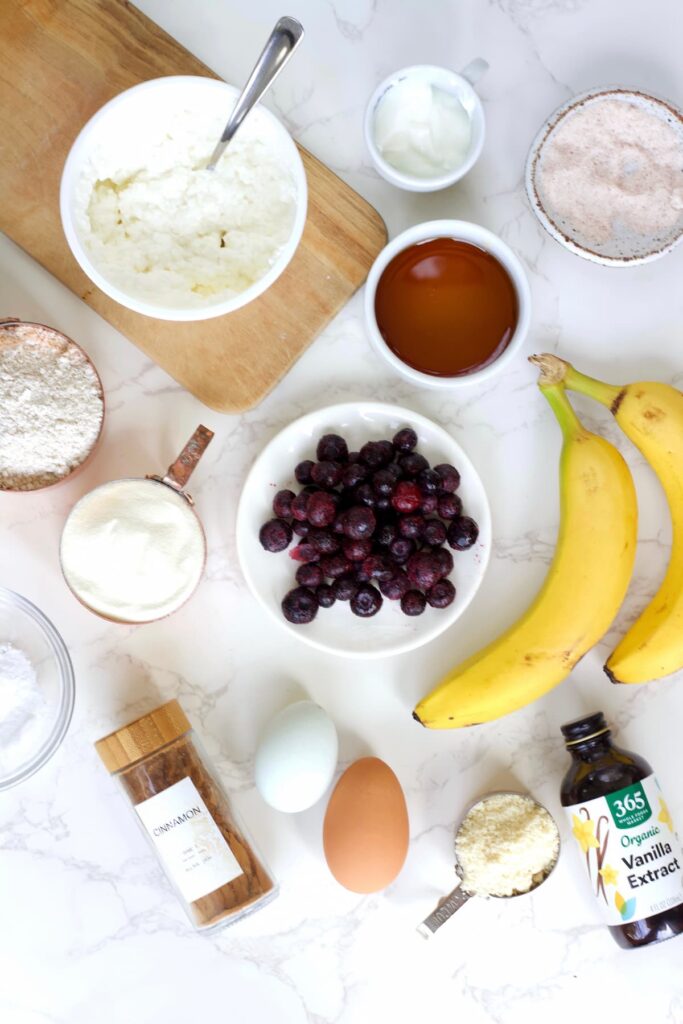 blueberry cottage cheese muffin ingredients like bananas, cottage cheese, greek yogurt, blueberries, maple syrup, eggs, protein powder and vanilla extract