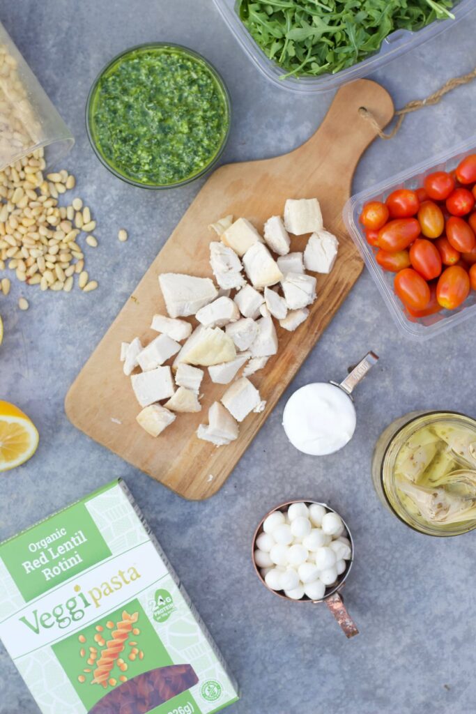 high protein pesto pasta salad ingredients like chicken, yogurt, artichoke hearts, tomatoes and pasta