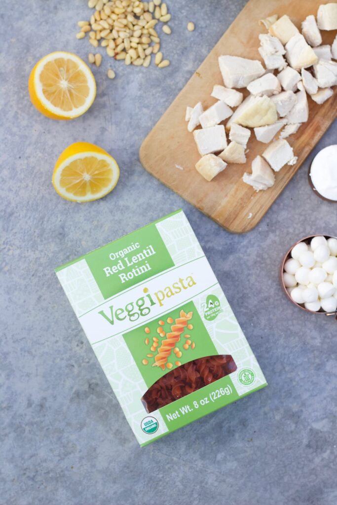 red lentil pasta brand next to diced chicken, lemon slices and pine nuts
