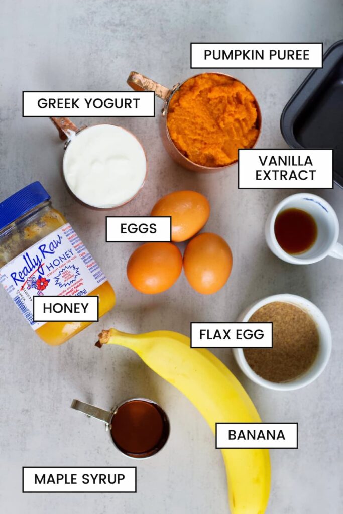 ingredients for a protein pumpkin loaf including banana, honey, flax egg, greek yogurt, pumpkin puree, eggs, maple syrup and vanilla exctract