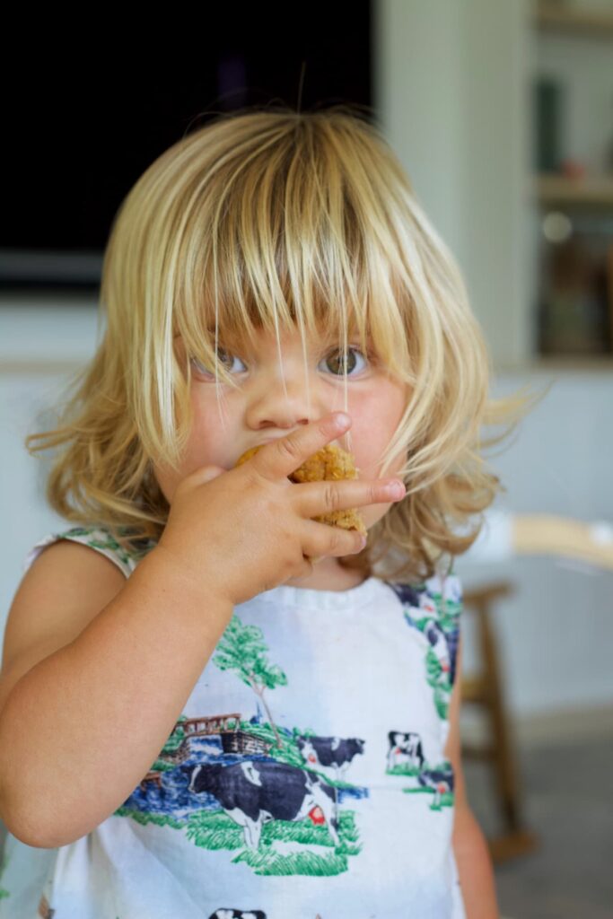 toddler girl eating a protein pumpkin muffin