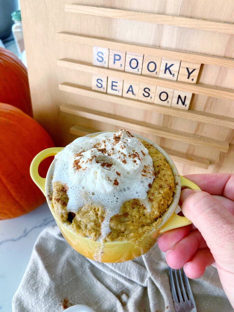 pumpkin spice mug cake in a mug with whipped cream topping