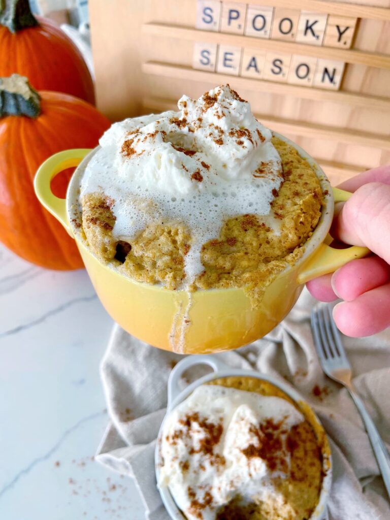 pumpkin spice mug cake in a mug with whipped cream topping