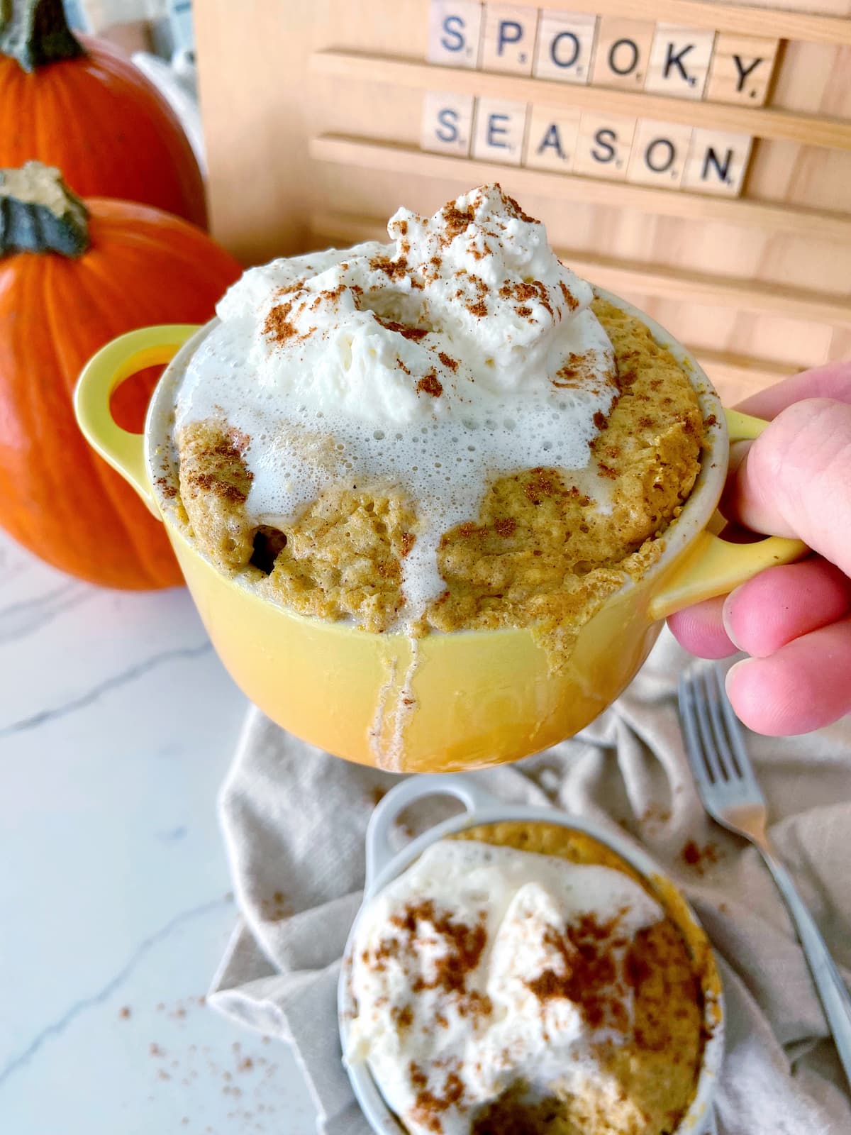 pumpkin spice mug cake in a mug with whipped cream topping