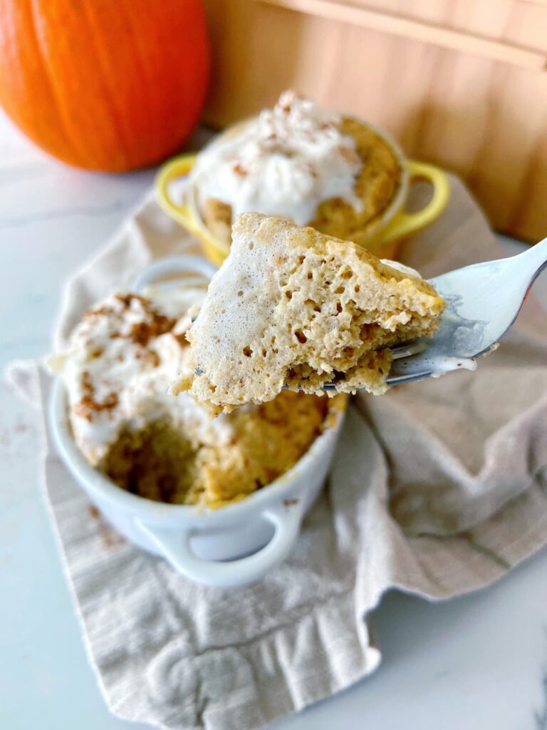 pumpkin spice mug cake in a mug with whipped cream topping close up