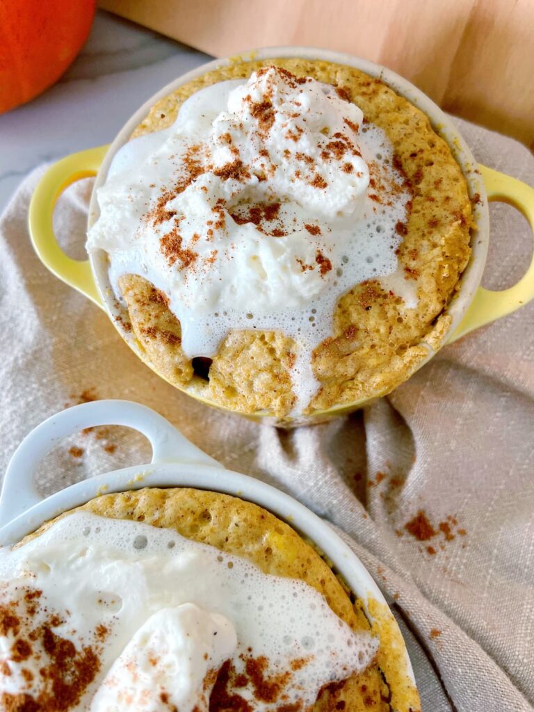 pumpkin spice mug cake in a mug with whipped cream topping close up