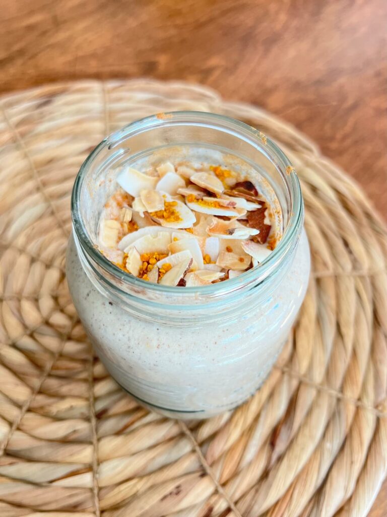 snickerdoodle protein smoothie in a glass with coconut flakes topping