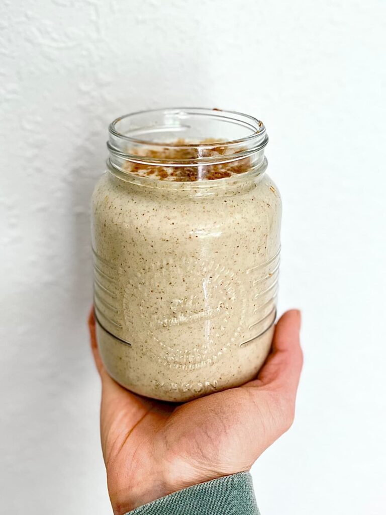 snickerdoodle protein smoothie in a glass with coconut flakes topping