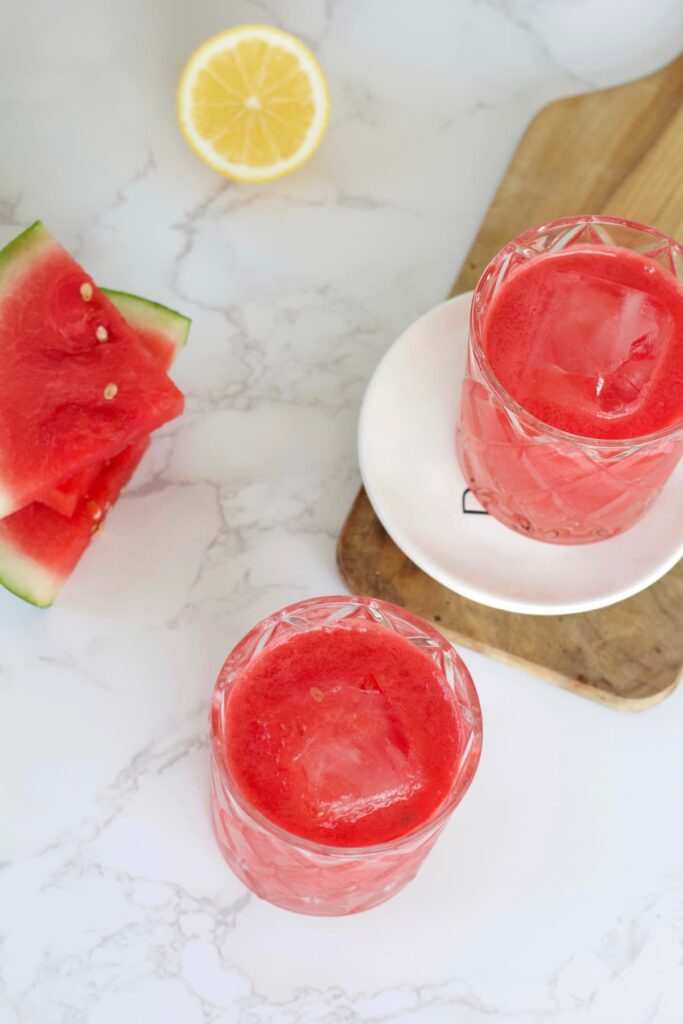 watermelon mocktail in glasses with watermelon and lemon next to it