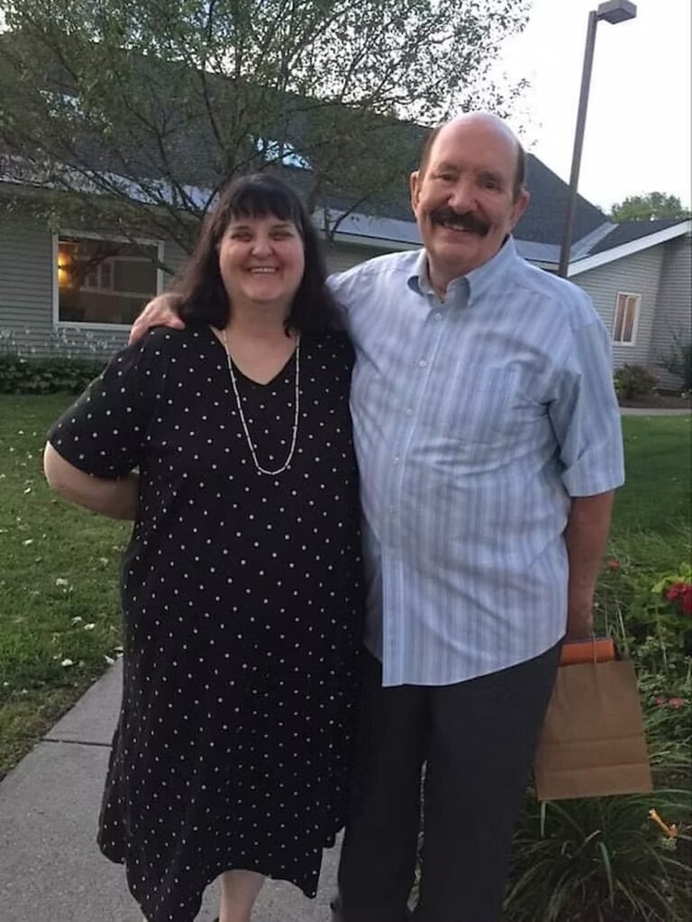 carolyn and her husband standing in front of a house