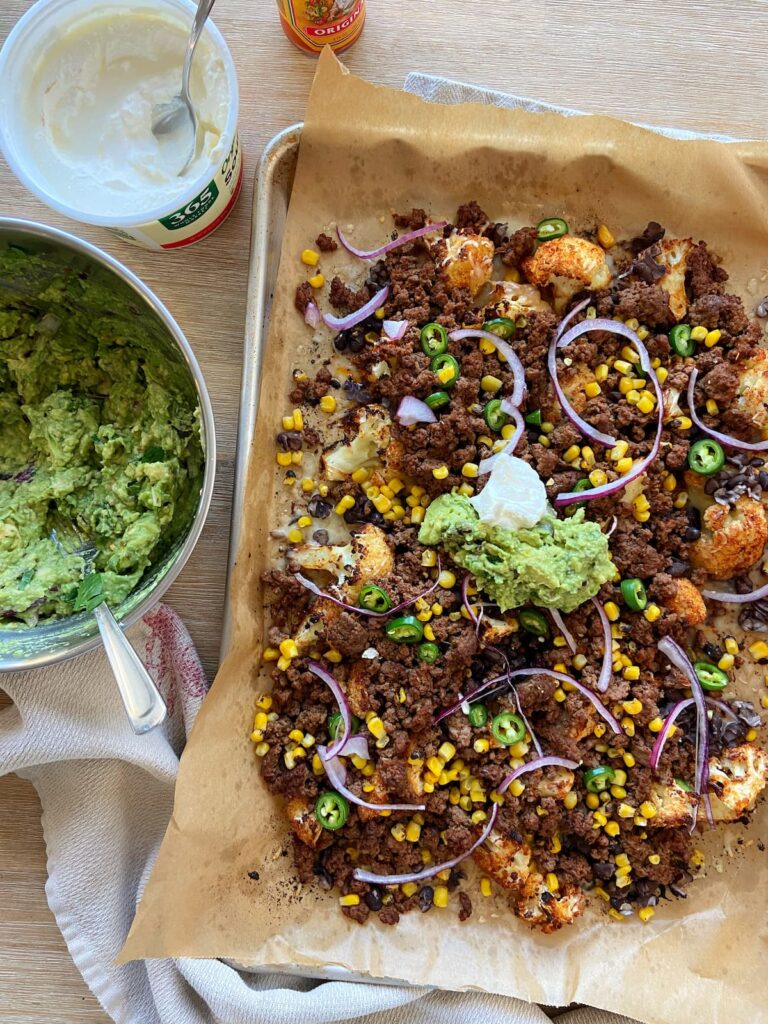 cauliflower nachos with guacamole, onions, ground beef, black beans and cheese