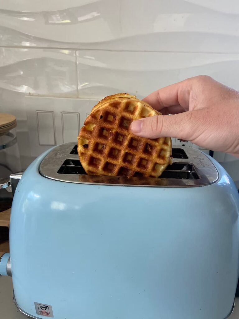 chocolate chip protein waffles being put into a toaster