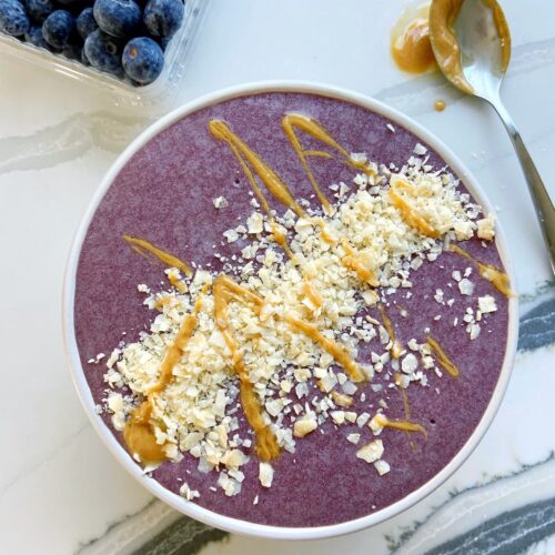 high protein acai bowl with coconut flakes and peanut butter drizzle topping