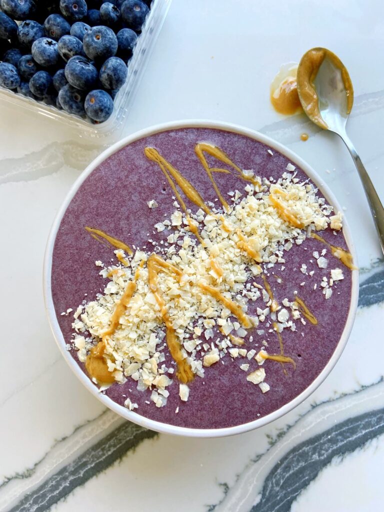 high protein acai bowl with coconut flakes and peanut butter drizzle topping