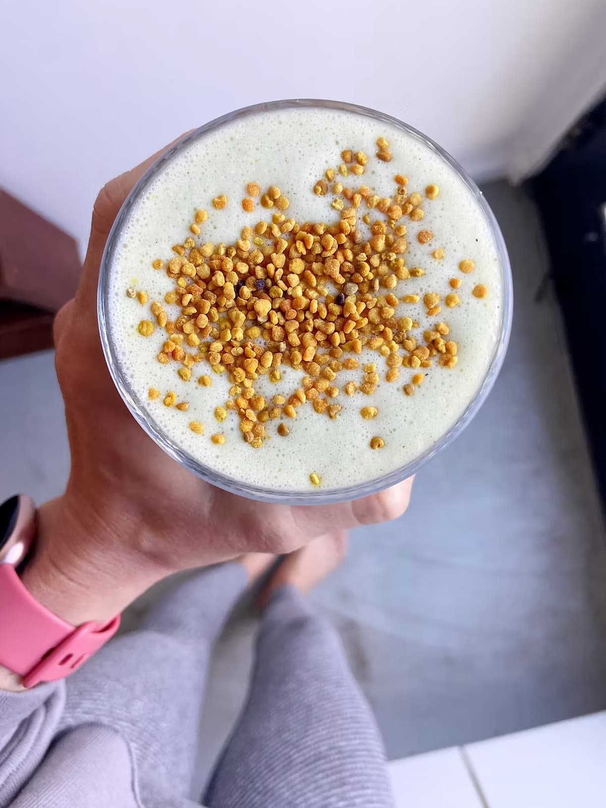 high protein green smoothie in a glass with bee pollen topping