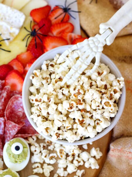 healthy popcorn in a bowl with a halloween skeleton hand in it