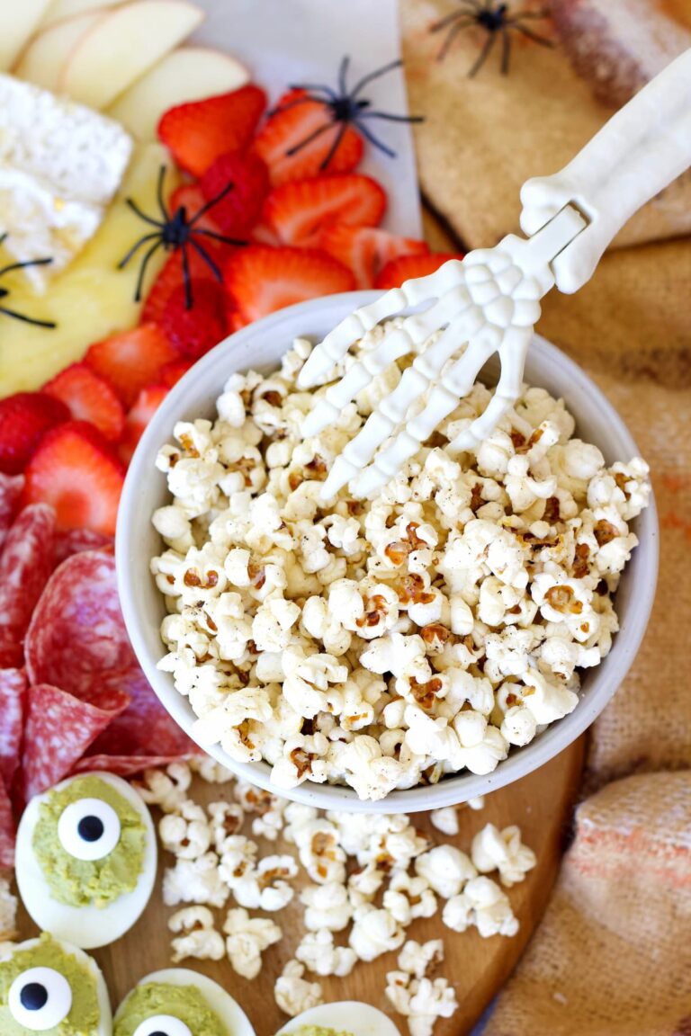 healthy popcorn in a bowl with a halloween skeleton hand in it