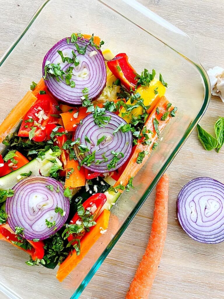 onions, bell pepper, carrots and zucchini with basil in a plate