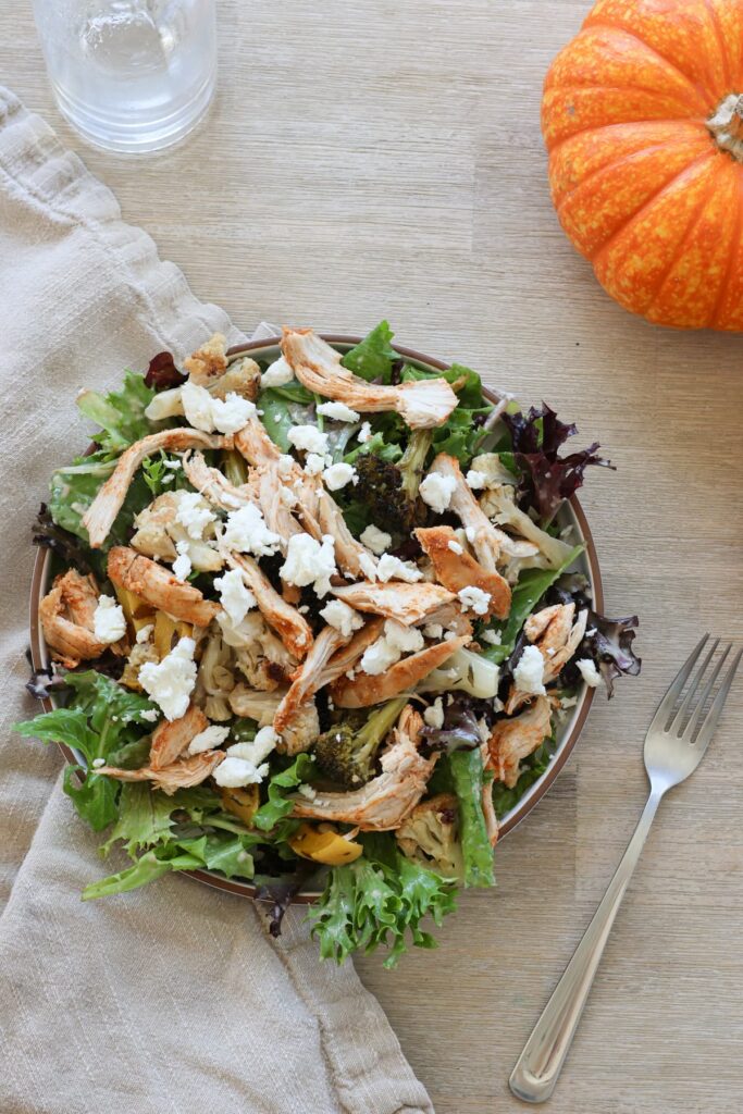 leftover thanksgiving salad with goat cheese on a plate with a fork and a pumpkin in the corner