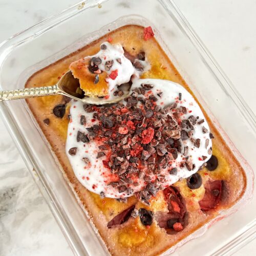 raspberry chocolate chip protein breakfast bars in a small glass container with greek yogurt and cacao nibs on top