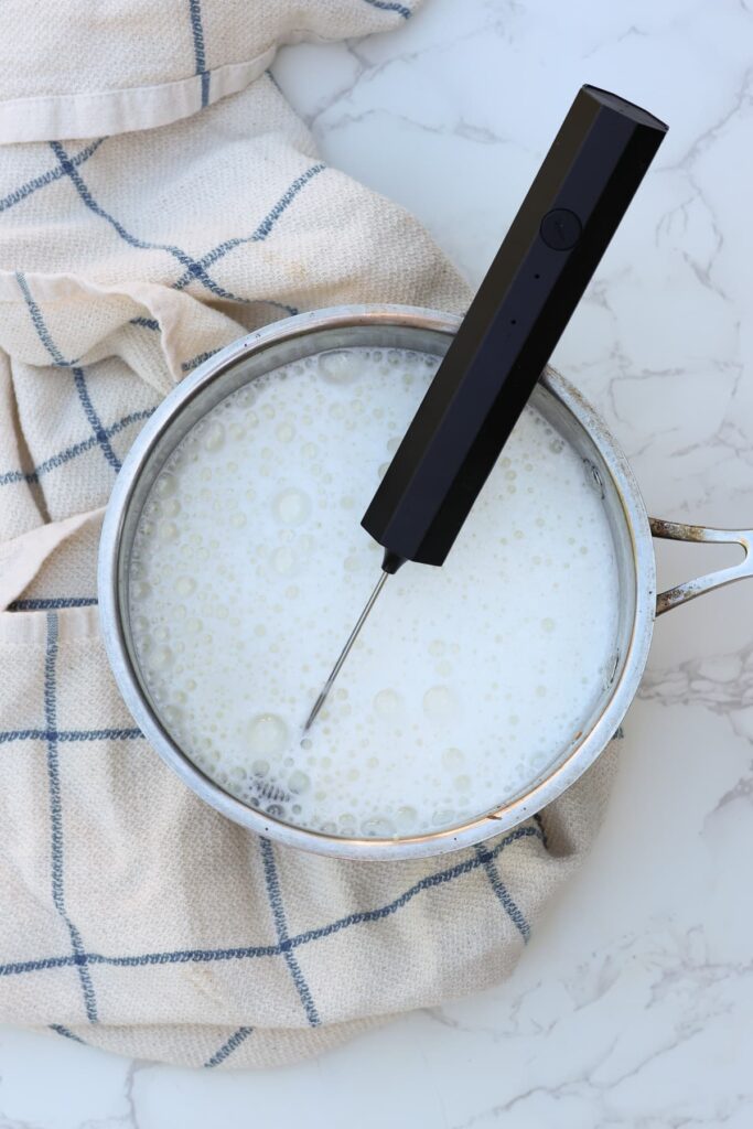 whole milk whisked with a coffee frother in a pot