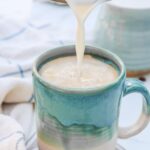 milk being poured into a mug with espresso