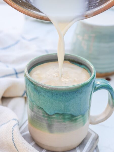 milk being poured into a mug with espresso