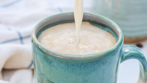 milk being poured into a mug with espresso