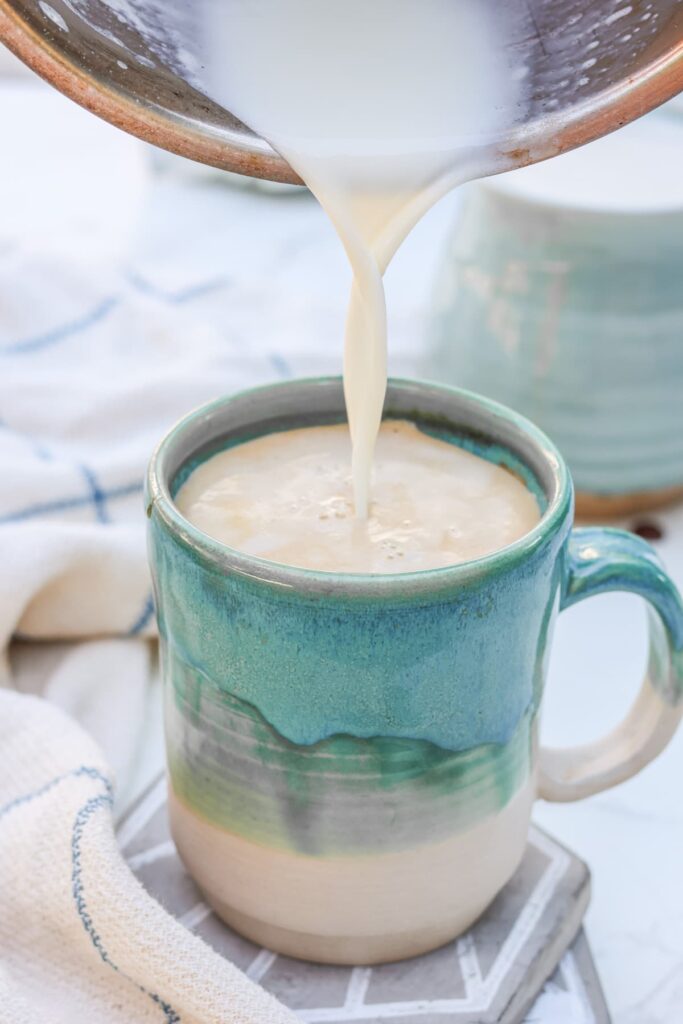milk being poured into a mug with espresso