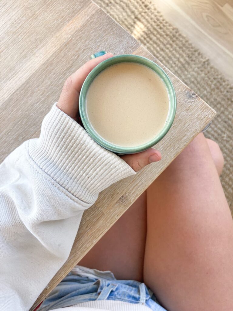 woman holding a protein coffee in a ceramic mug