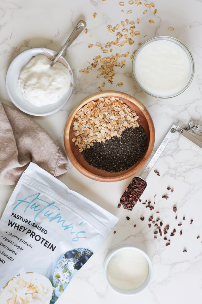 high protein high fiber overnight oats ingredients with yogurt, protein powder, oats, chia seeds, milk and cacao nibs