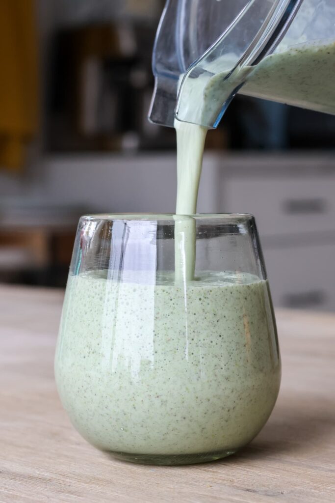green protein smoothie being poured into a glass