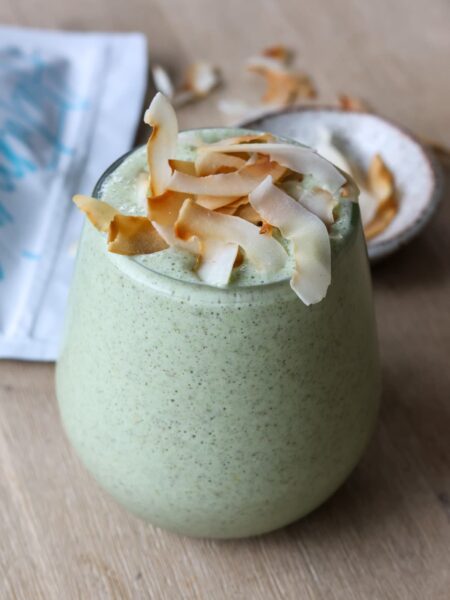 green protein smoothie with toasted coconut flakes topping