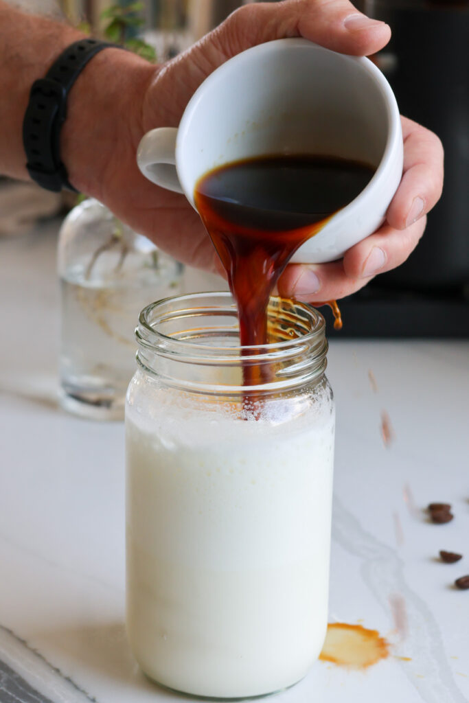 pouring coffee into protein milk for an iced protein coffee