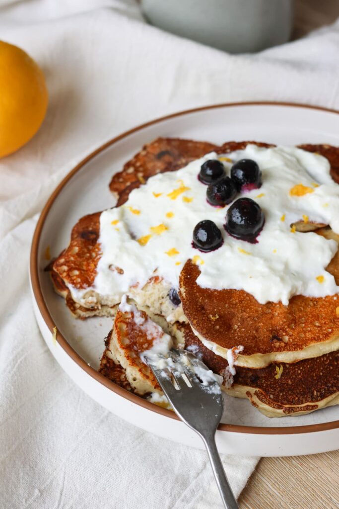 blueberry lemon protein pancakes on a plate with greek yogurt drizzle