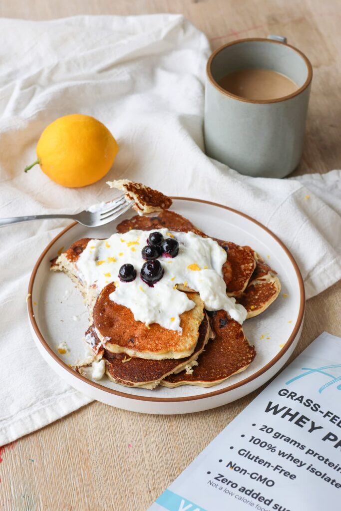 blueberry lemon protein pancakes on a plate with greek yogurt drizzle