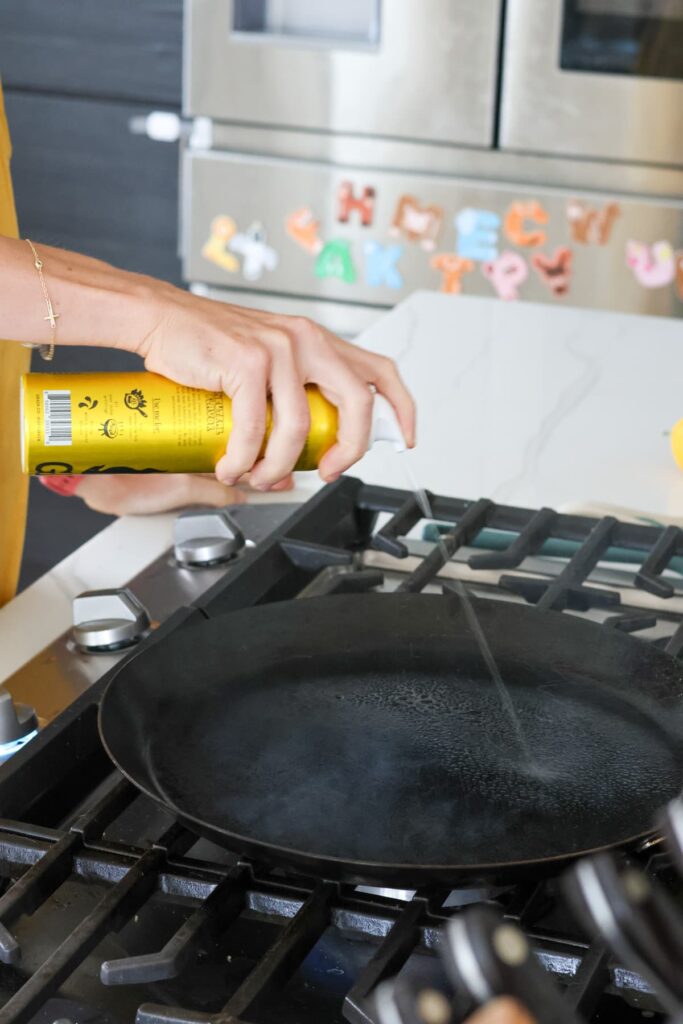 spraying a hot pan with olive oil