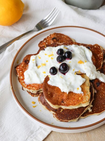 blueberry lemon protein pancakes on a plate with greek yogurt drizzle