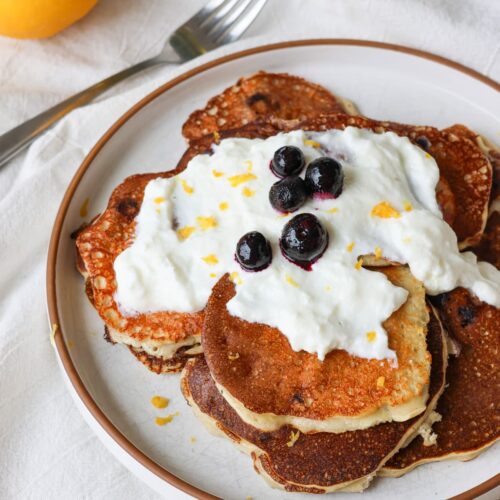 blueberry lemon protein pancakes on a plate with greek yogurt drizzle