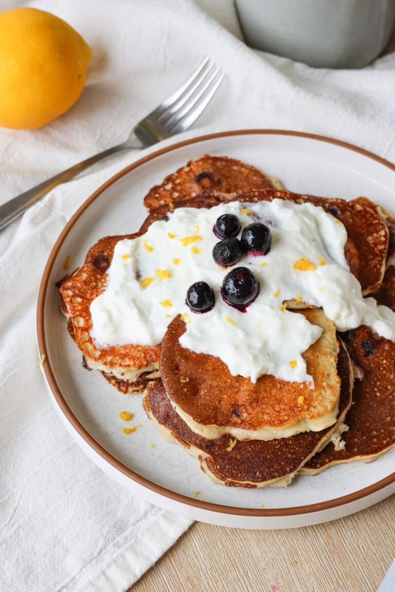 blueberry lemon protein pancakes on a plate with greek yogurt drizzle