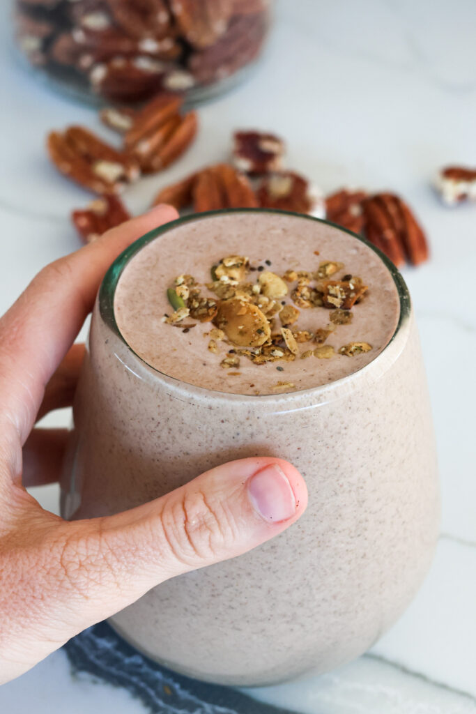 chocolate protein shake in a glass with toppings being held in a hand