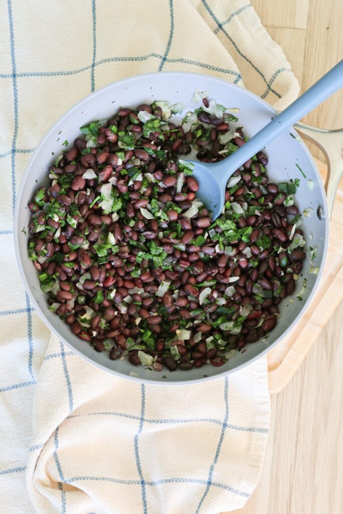 black beans with cilantro and onion and poblano in a pan with a spoon