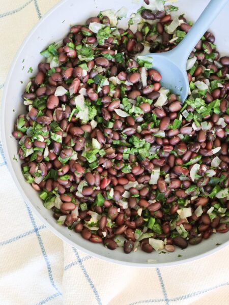 black beans with cilantro and onion and poblano in a pan with a spoon