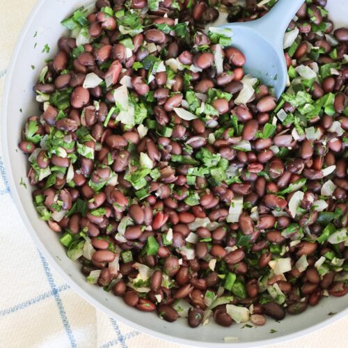 black beans with cilantro and onion and poblano in a pan with a spoon