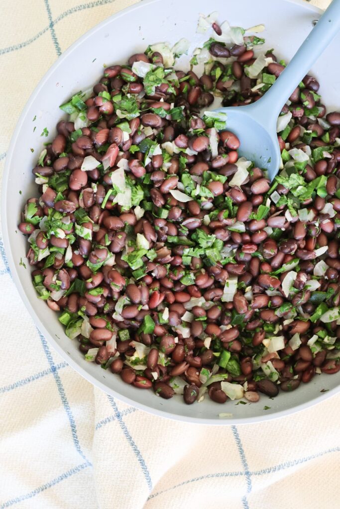black beans with cilantro and onion and poblano in a pan with a spoon
